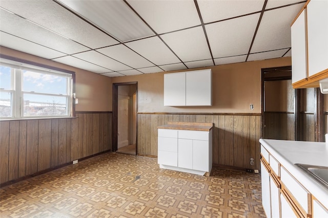 kitchen featuring a drop ceiling and white cabinetry