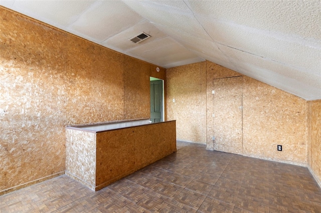 bonus room with dark parquet floors, a textured ceiling, and vaulted ceiling