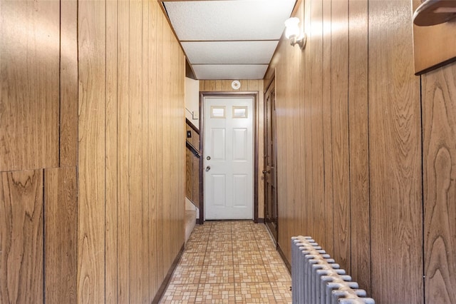 entryway with wooden walls, light tile floors, and radiator