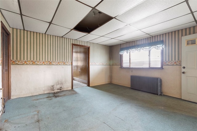 basement with radiator and a paneled ceiling