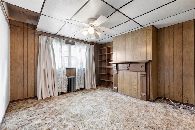 carpeted empty room with wooden walls and ceiling fan