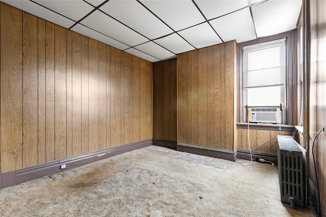 spare room with wooden walls, a paneled ceiling, carpet, and radiator