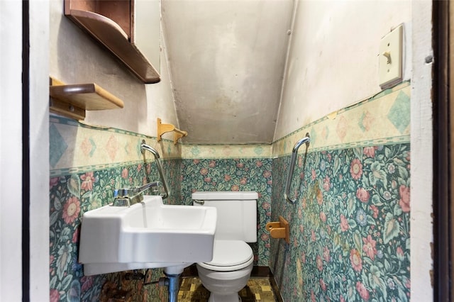 bathroom featuring toilet, vaulted ceiling, tile floors, and sink