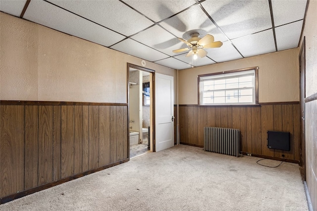 unfurnished room featuring ceiling fan, a paneled ceiling, light colored carpet, and radiator