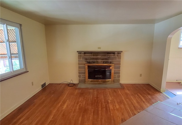 unfurnished living room featuring wood-type flooring and a stone fireplace