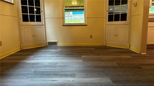 unfurnished dining area with dark wood-style floors, visible vents, and baseboards