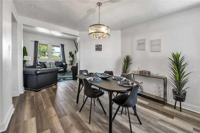 dining area featuring a notable chandelier, a textured ceiling, and dark hardwood / wood-style floors