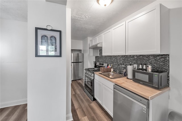 kitchen with appliances with stainless steel finishes, sink, white cabinets, tasteful backsplash, and dark hardwood / wood-style flooring