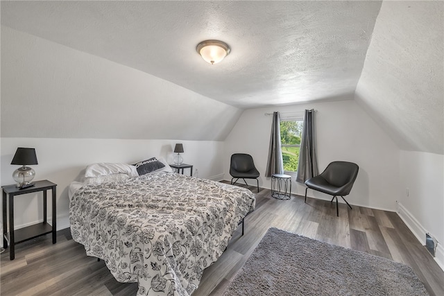 bedroom with dark hardwood / wood-style floors, vaulted ceiling, and a textured ceiling