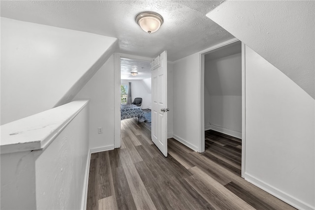 additional living space featuring a textured ceiling and dark hardwood / wood-style flooring