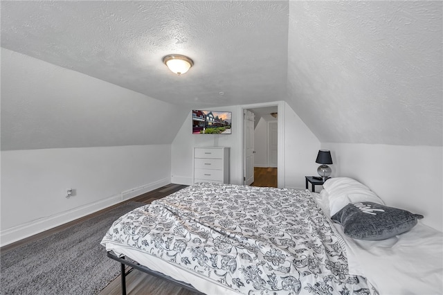 bedroom featuring dark hardwood / wood-style flooring, vaulted ceiling, and a textured ceiling