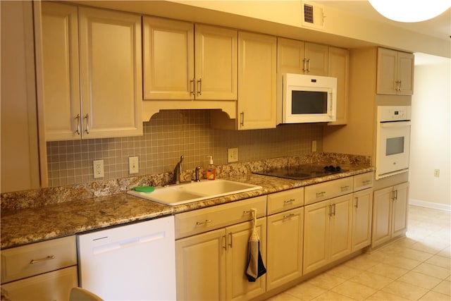 kitchen with decorative backsplash, light tile patterned floors, white appliances, and sink