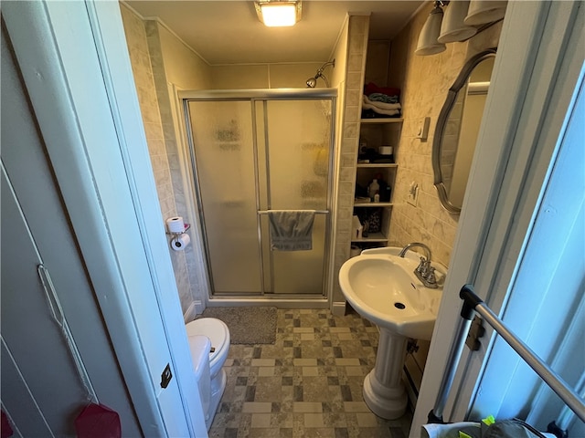 bathroom featuring a shower with door, sink, tile floors, and toilet