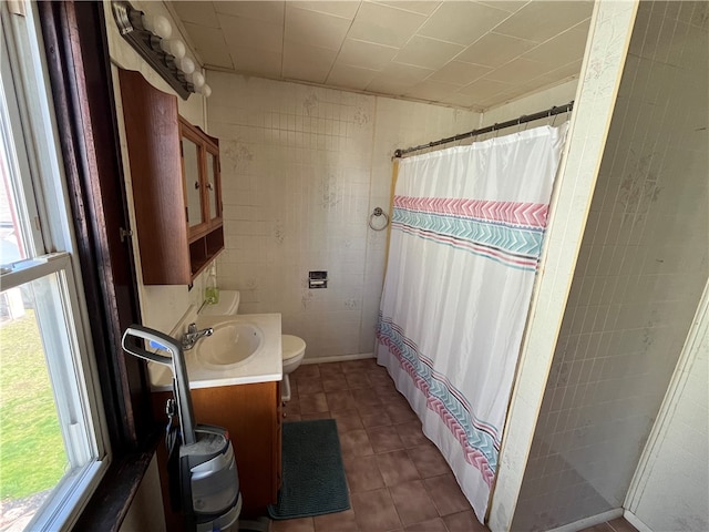 bathroom featuring a healthy amount of sunlight, vanity, toilet, and tile flooring