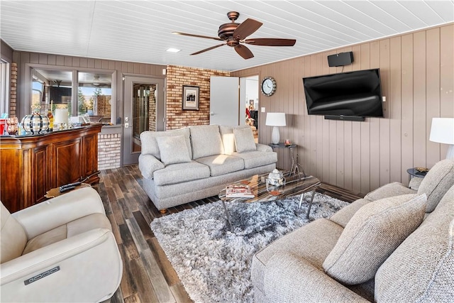 living room with dark hardwood / wood-style floors, ceiling fan, and wooden walls