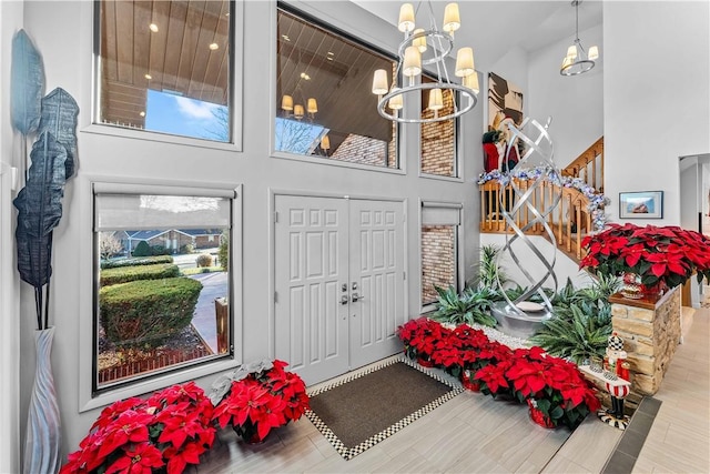 foyer with light hardwood / wood-style floors, a high ceiling, and an inviting chandelier