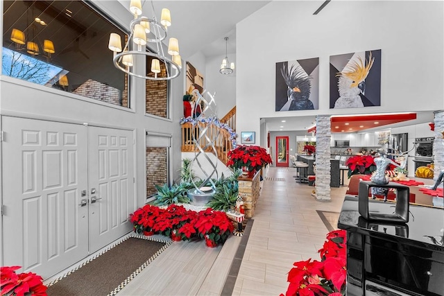 foyer with a towering ceiling, decorative columns, and an inviting chandelier