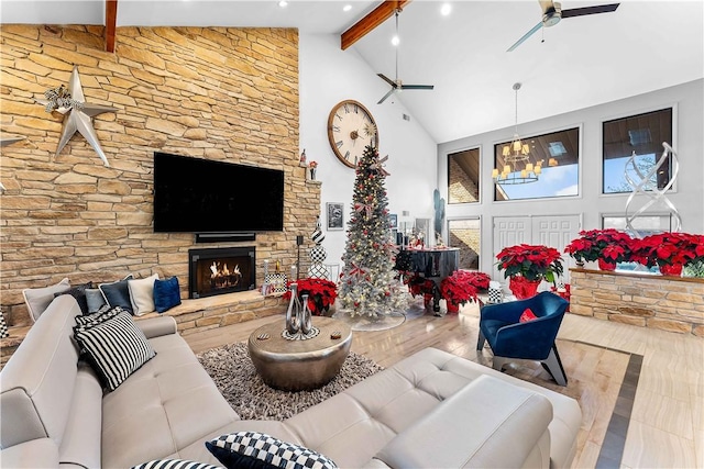 living room with high vaulted ceiling, a stone fireplace, beam ceiling, wood-type flooring, and a chandelier