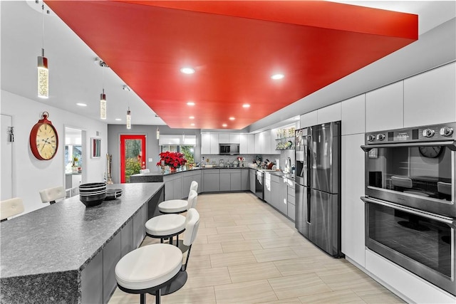 kitchen with gray cabinetry, white cabinets, tasteful backsplash, decorative light fixtures, and stainless steel appliances