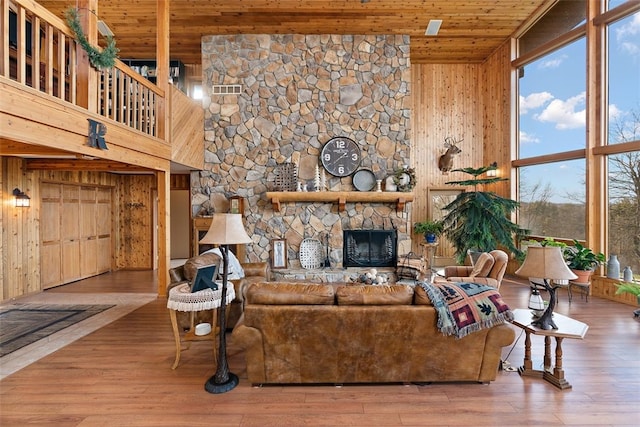 living room with a fireplace, high vaulted ceiling, wood ceiling, wooden walls, and wood-type flooring