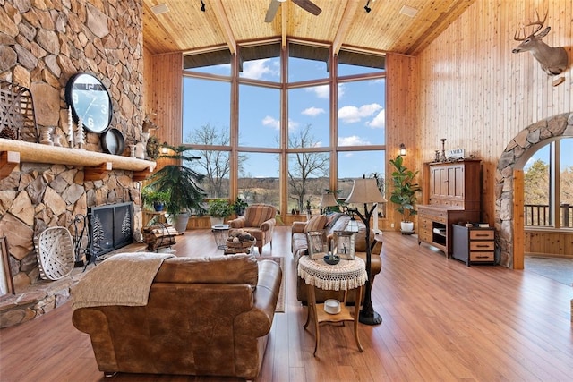 living room featuring high vaulted ceiling, a fireplace, light hardwood / wood-style flooring, wood ceiling, and ceiling fan