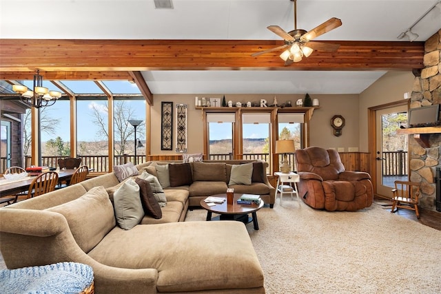 living room with ceiling fan with notable chandelier, a fireplace, vaulted ceiling with beams, and track lighting