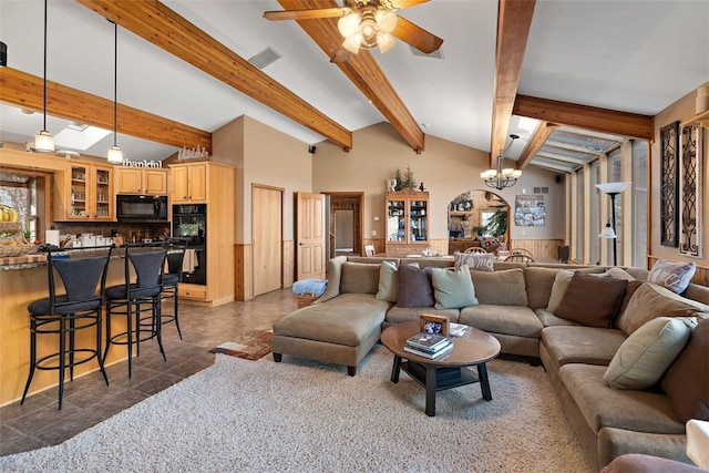 living room featuring ceiling fan with notable chandelier, tile floors, and vaulted ceiling with beams