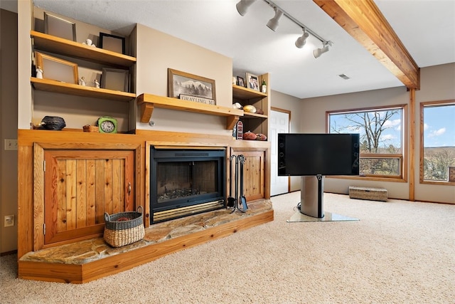 carpeted living room with beam ceiling and track lighting