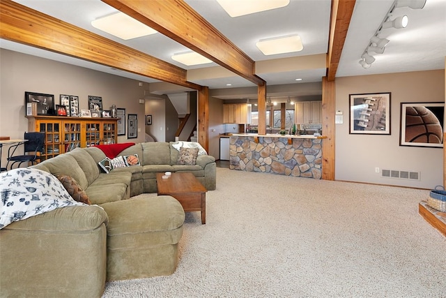 carpeted living room featuring rail lighting and beam ceiling