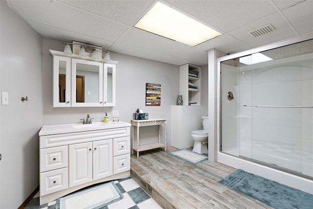 bathroom with an enclosed shower, a drop ceiling, oversized vanity, hardwood / wood-style flooring, and toilet