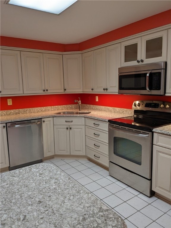 kitchen featuring stainless steel appliances, light tile flooring, and sink