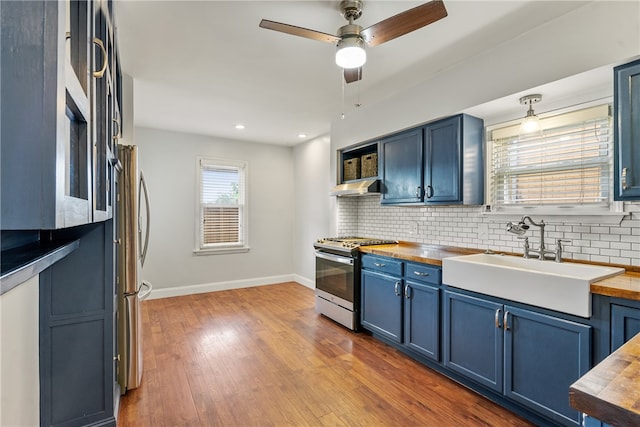 kitchen featuring dark wood-type flooring, gas range, butcher block countertops, ceiling fan, and blue cabinetry