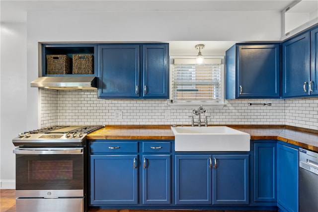 kitchen featuring appliances with stainless steel finishes, sink, blue cabinetry, wall chimney range hood, and tasteful backsplash