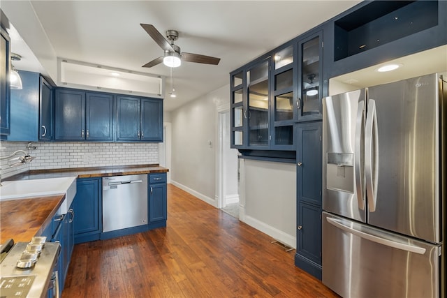 kitchen featuring appliances with stainless steel finishes, wood counters, dark hardwood / wood-style flooring, and blue cabinetry