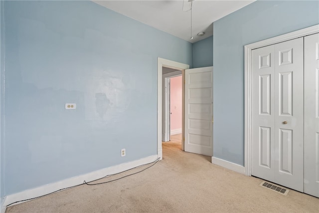 unfurnished bedroom with a closet and light colored carpet