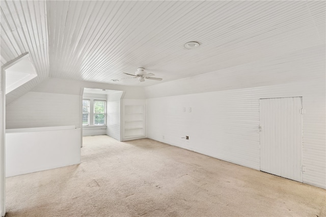 additional living space featuring built in shelves, ceiling fan, lofted ceiling, and light carpet