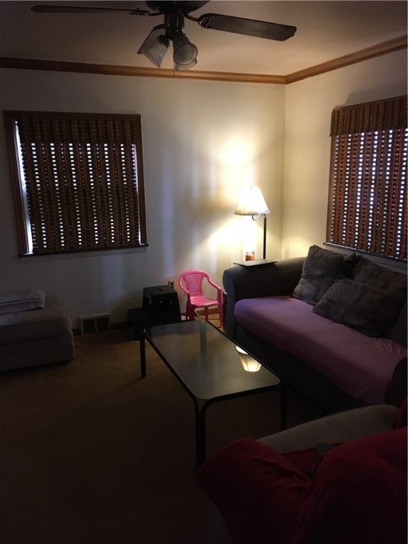 living room with ornamental molding, carpet floors, and ceiling fan