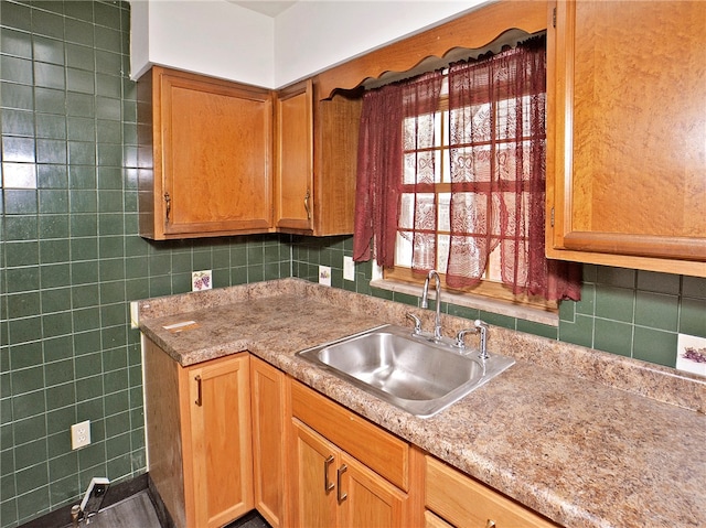 kitchen with sink, backsplash, light stone countertops, and tile walls