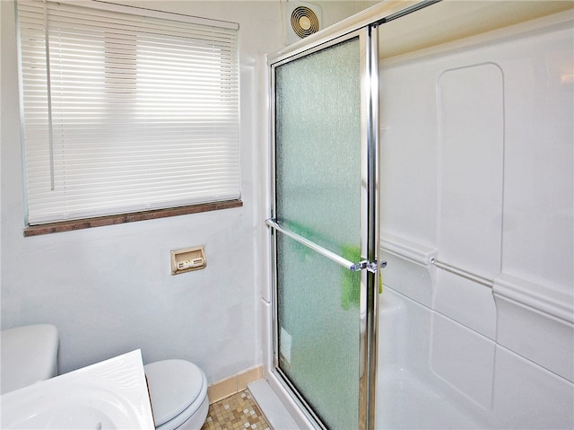 bathroom featuring tile floors, toilet, and a shower with door