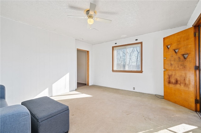 sitting room featuring ceiling fan, a textured ceiling, and light colored carpet