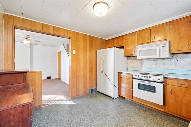 kitchen featuring ceiling fan, wooden walls, and white appliances