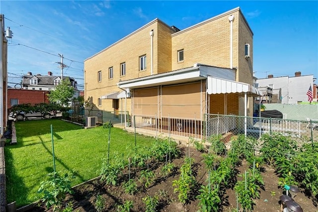 rear view of house with central air condition unit and a lawn