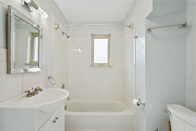 full bathroom featuring tiled shower / bath combo, toilet, and vanity