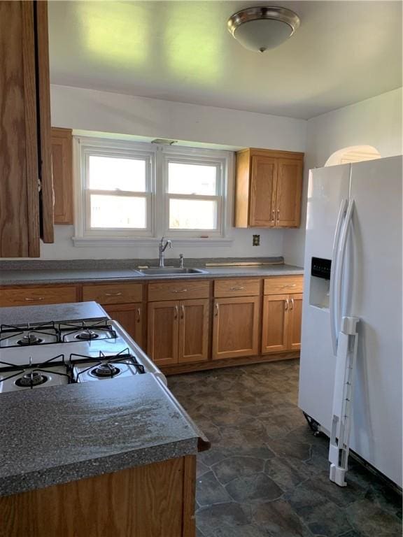 kitchen featuring dark stone countertops, white appliances, and sink