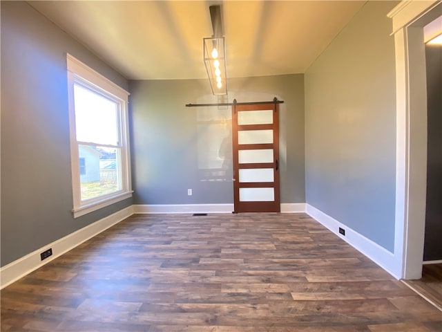 unfurnished room with dark hardwood / wood-style flooring and a barn door