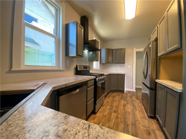 kitchen featuring dark hardwood / wood-style floors, stainless steel appliances, wall chimney exhaust hood, and gray cabinets