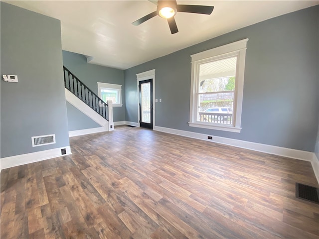 empty room with ceiling fan, plenty of natural light, and dark hardwood / wood-style flooring