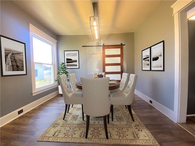 dining space featuring a barn door and dark hardwood / wood-style flooring