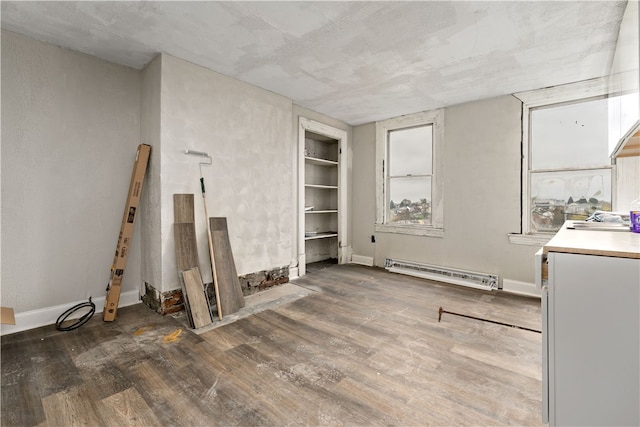 interior space featuring built in shelves, dark wood-type flooring, and a baseboard radiator