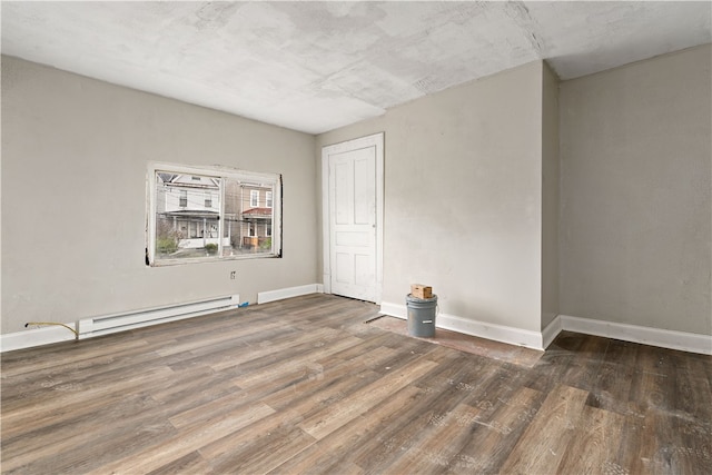 empty room with baseboard heating and dark wood-type flooring